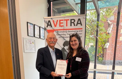 award winner stands in front of banner
