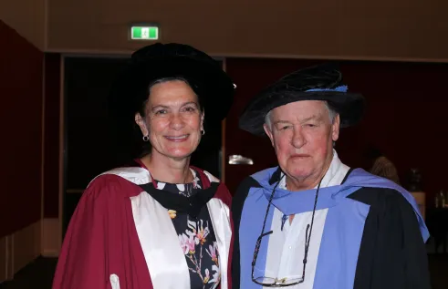Two professors pose in regalia 