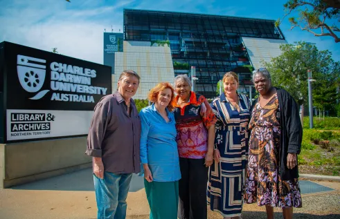 Five women stand outside the front of Charles Darwin University's new campus in the Darwin CBD. 