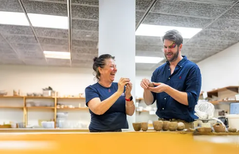Two people making pots from clay