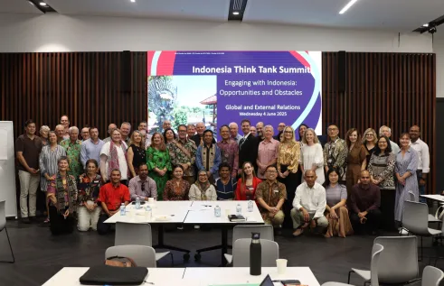Group of 30+ people from across Australia, Indonesia and Timor-Leste standing in front of a white board that says 'Indonesia Think Tank Summit.'