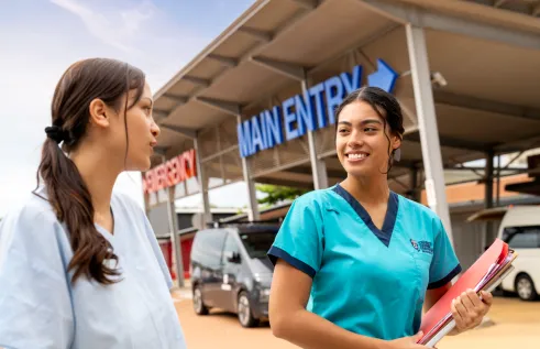 Two students in nursing uniforms smiling in front of RDH