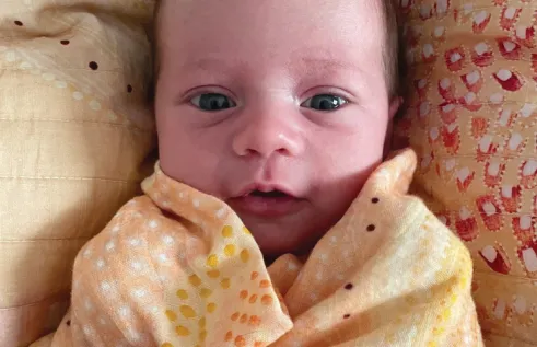 Happy Aboriginal baby wrapped in colourful linen sheets
