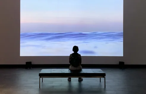 Art gallery visitor sitting on a bench viewing artwork 