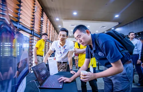 Students and staff at the CDU IT Code Fair looking at a laptop.