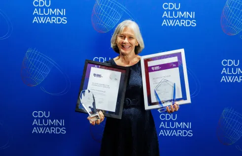 Esther stands with her two awards and certificates 