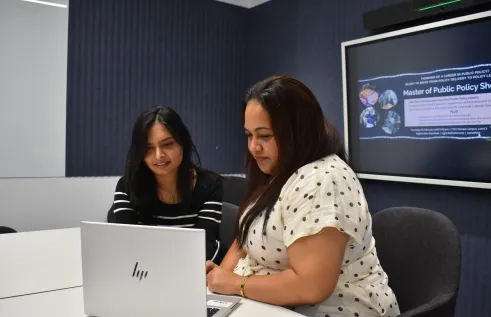 two students looking at a laptop talking