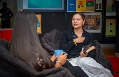 Two students seated down with one students back facing the front