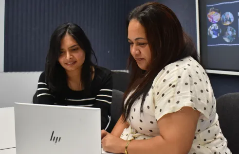 Two women looking at a laptop screen in a small room