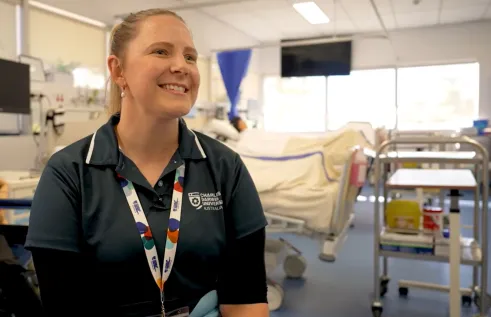 Nursing lecturer sits in front of hospital beds