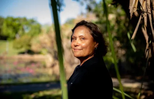 Picture of a woman looking towards camera with natural flora in the back