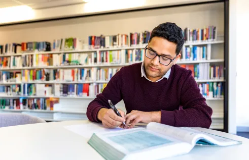 Student studying with a textbook at a desk