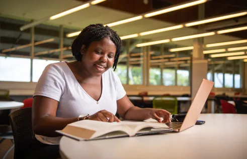Student with textbook and laptop