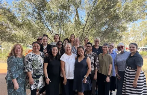 group of women stand in front of foliage
