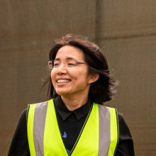 Dr Jady Li, head and shoulders, wearing hi-vis vest, with brown background