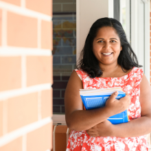 Indigenous Australian teacher holding books in regional school