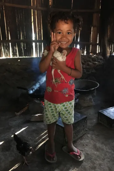 A child holding a chicken inside a building