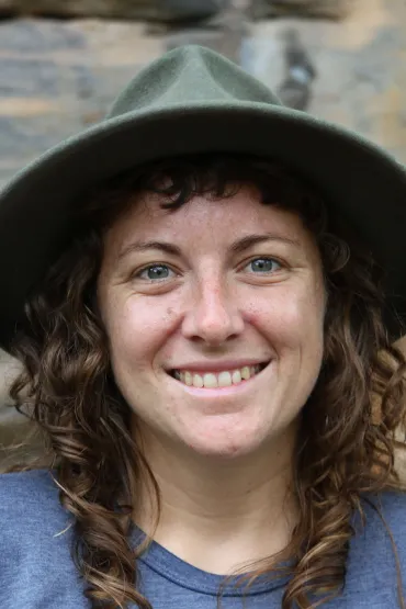 Jennifer Macdonald head and shoulders, wearing hat with stone wall in background
