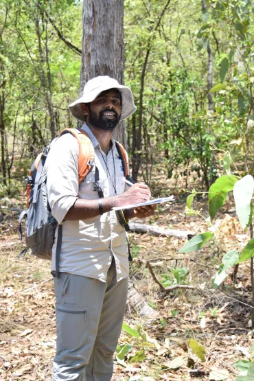 Man standing in forest writing in a notebook