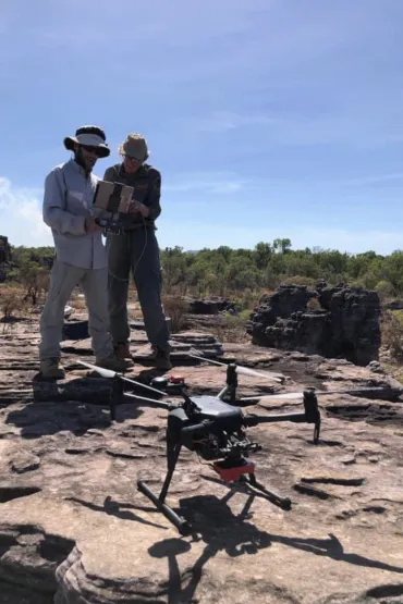 Drone standing on rock with two people standing behind it holding controller