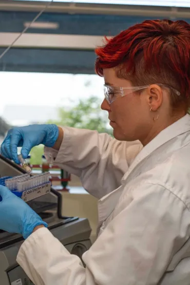 Dr Alea Rose in a laboratory, holding a test tube and a blue rack of test tubes