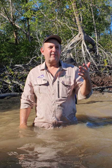 Dr Ben Brown standing waist deep in water with mangrove trees behind