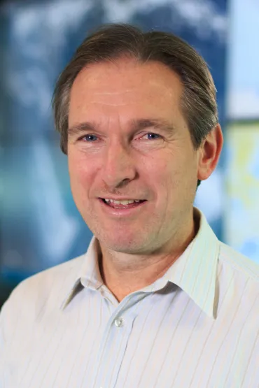 Blair Trewin head and shoulders with out of focus blue background