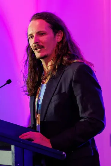 Dylan stands at lectern speaking to crowd