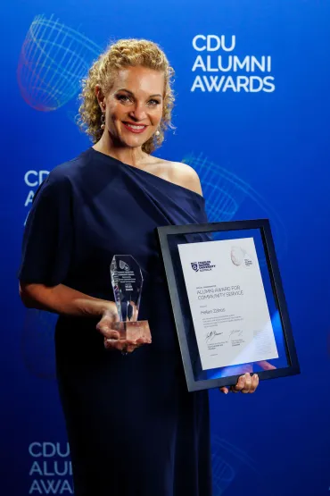 Helen stands holding her certificate and trophy