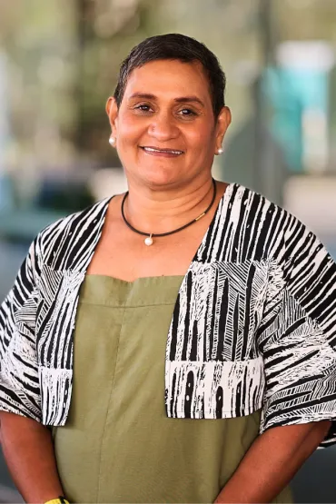 smiling yvette with green linen and cropped jacket in front of waterfront campus