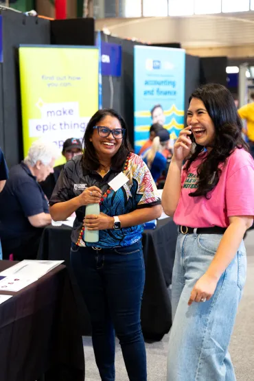 2 women laughing front of a information stall